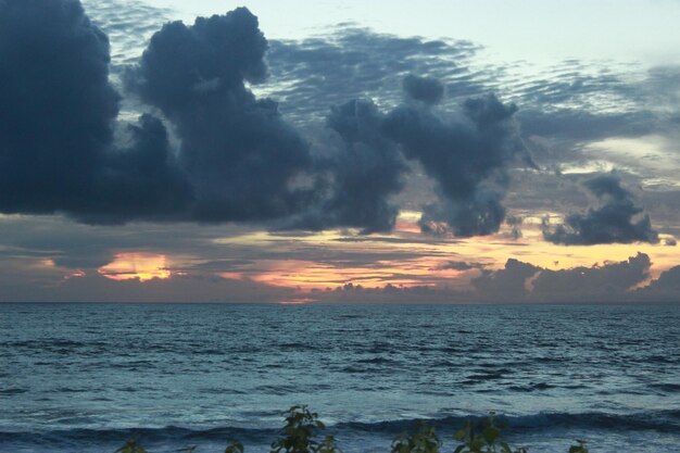 Um pôr do sol sobre o oceano com um céu nublado e algumas nuvens
