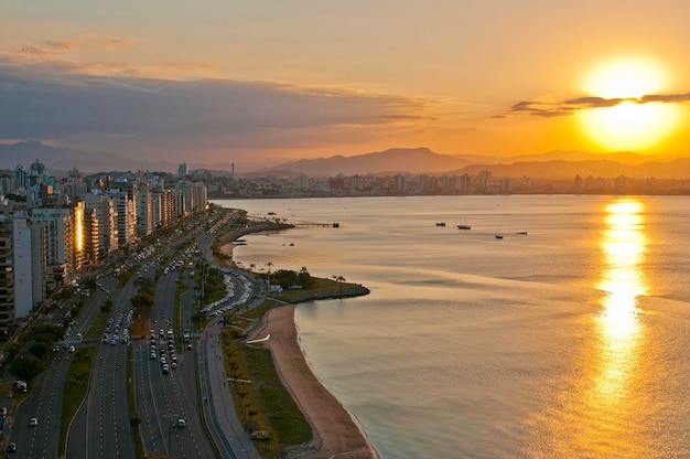 Foto um pôr do sol sobre o oceano com uma cidade ao fundo