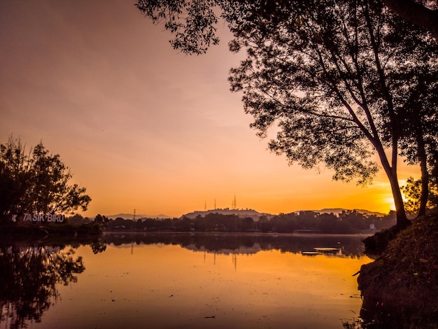 Um pôr do sol sobre um lago com um grande edifício ao fundo