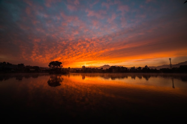 Um pôr do sol sobre um lago com um reflexo do céu e o sol está se pondo.