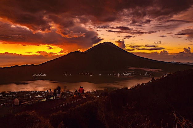 Um pôr do sol sobre um vulcão com uma montanha ao fundo