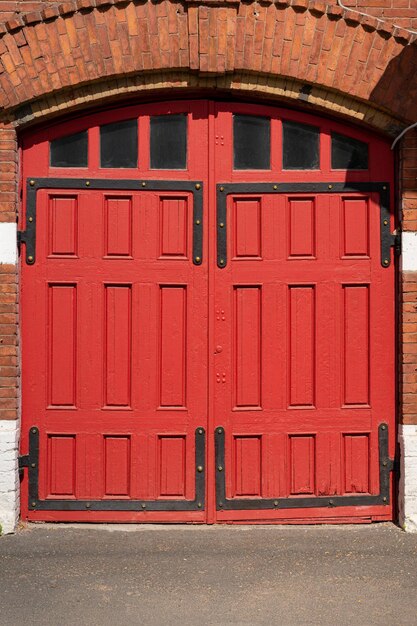 Um portal de madeira vermelha, arco e janela da antiga estação de bombeiros com decorações metálicas