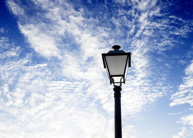 Um poste de luz com um céu azul e nuvens ao fundo
