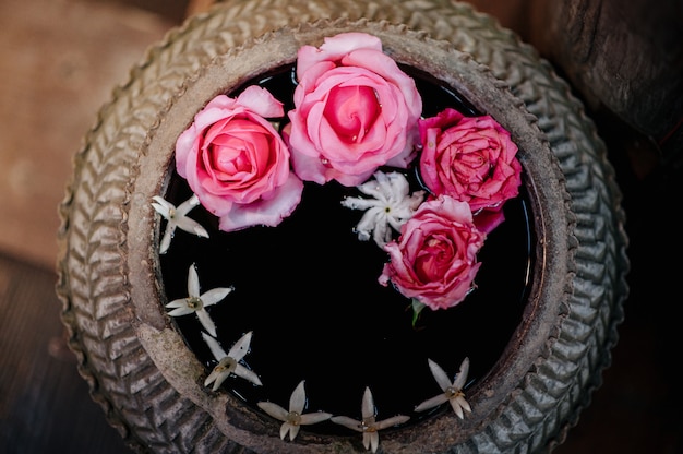 Um pote de água com rosas e outras flores flutuando lá