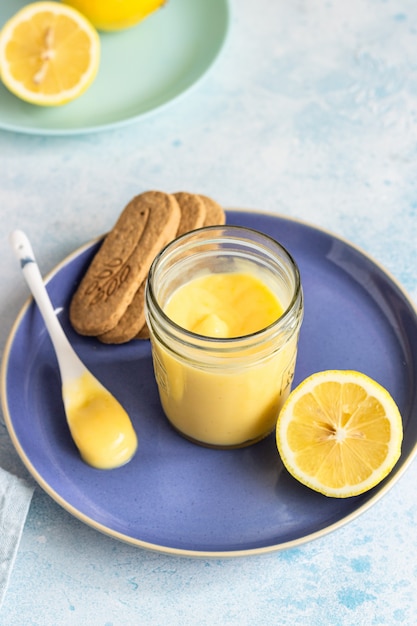 Um pote de coalhada de limão ou creme e biscoitos num prato azul.