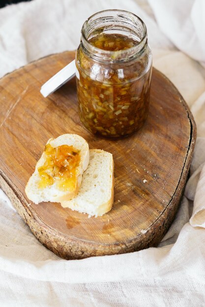 Um pote de marmelada com um pedaço de pão e um pote de marmelada ao lado.