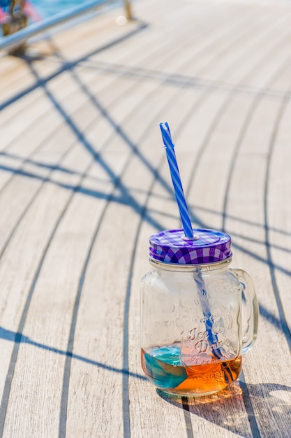 Um pote transparente com uma bebida agradável fica no convés do iate durante o resto.