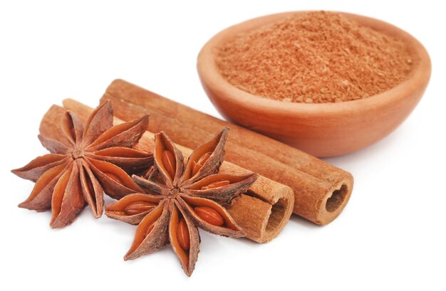 Um pouco de canela aromática com anis estrelado e especiarias em uma tigela sobre fundo branco