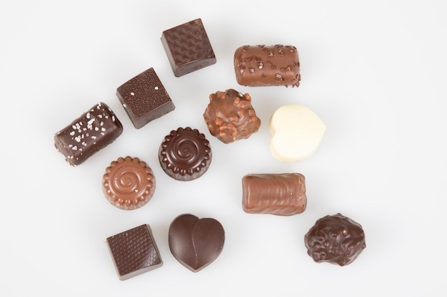 Foto um pouco de chocolate escuro e de leite em diferentes formas de pralinês em vista superior em fundo branco