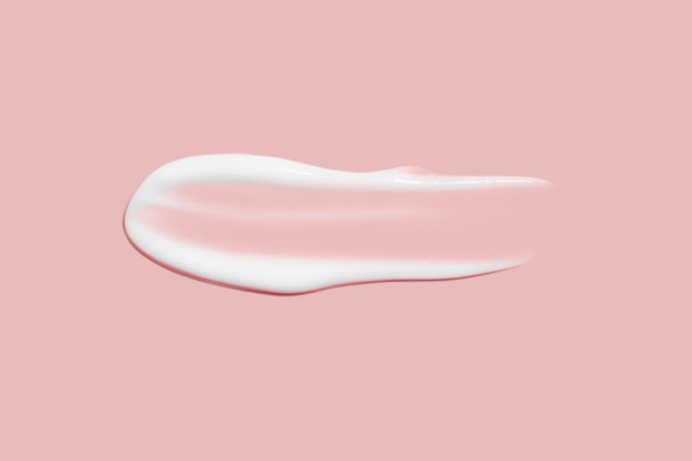 Um pouco de creme cosmético Superfície lisa e clara Textura de creme para barrar Esfregaço de creme líquido Sobre um fundo rosa