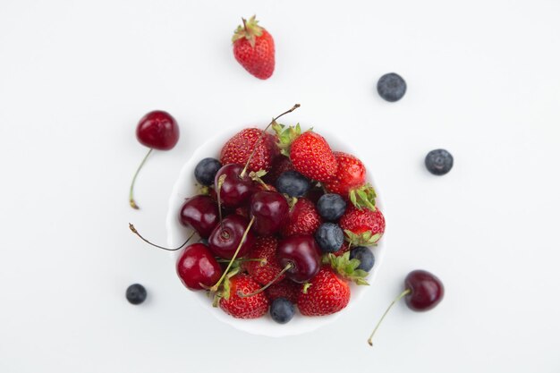 Um prato branco com cerejas suculentas, morangos e mirtilos decorados