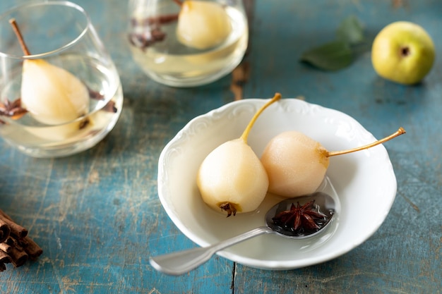 Um prato branco com deliciosas peras em vinho em uma mesa de madeira