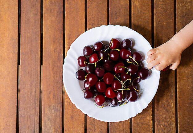 Foto um prato branco com muitas cerejas vermelhas sobre o antigo fundo de madeira marrom