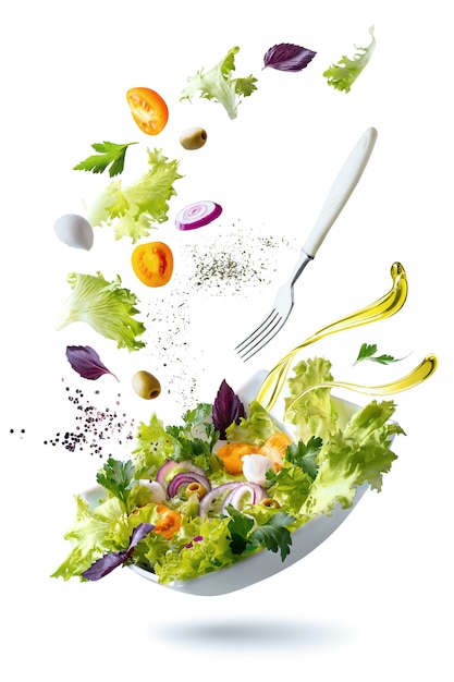 Um prato branco com salada e flutuando no ar ingredientes: azeitonas, alface, cebola, tomate, queijo mussarela, salsa, manjericão e azeite de oliva.