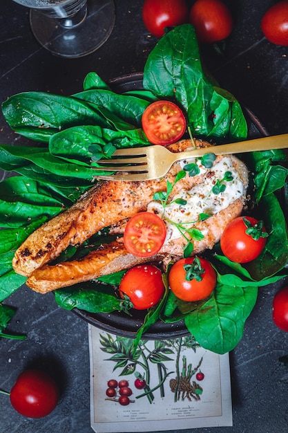 Um prato com espinafre cru verde fresco e tomates de salmão selvagem fritos e molho de queijo creme