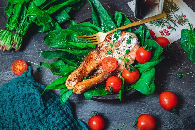 Um prato com espinafre cru verde fresco e tomates de salmão selvagem fritos e molho de queijo creme