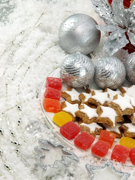 Um prato de biscoitos de natal com uma bugiganga de prata e uma bola de natal de prata.