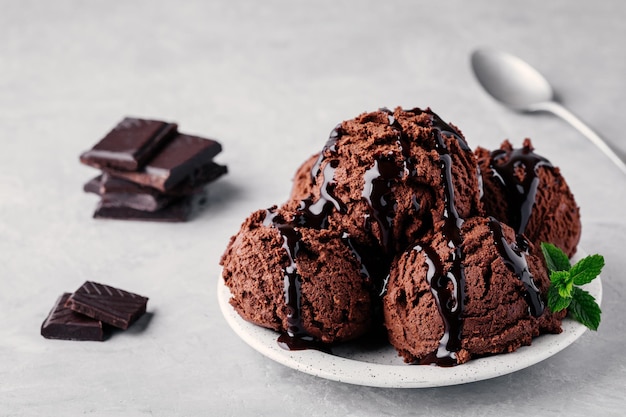 Um prato de bolas de sorvete de chocolate com calda de chocolate na luz de fundo