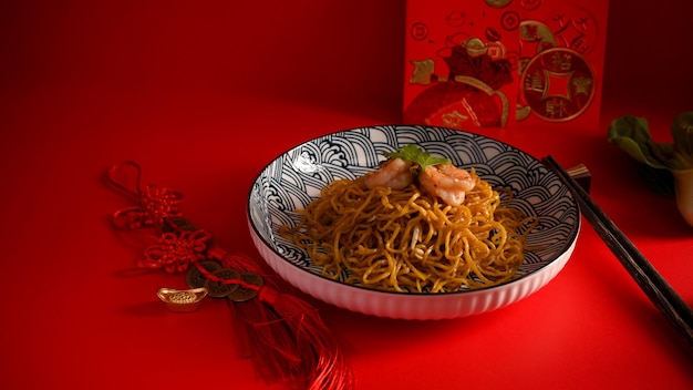 Um prato de chow mein com palitos de camarão. Amuletos da sorte chineses Cartão de ano novo chinês