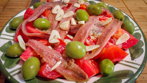 Um prato de comida com azeitona verde e pimenta vermelha