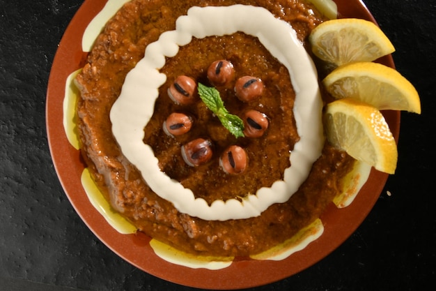 Foto um prato de comida com um creme branco e um molho vermelho com uma rodela de limão por cima.