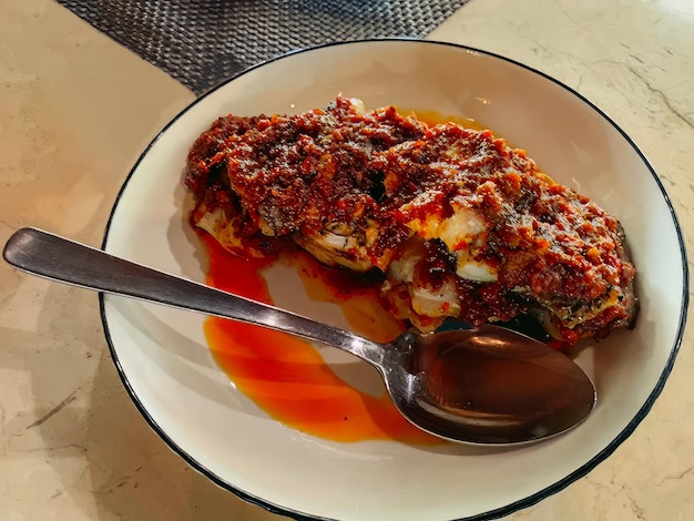 Um prato de comida com uma colher sobre ele e uma colher ao lado