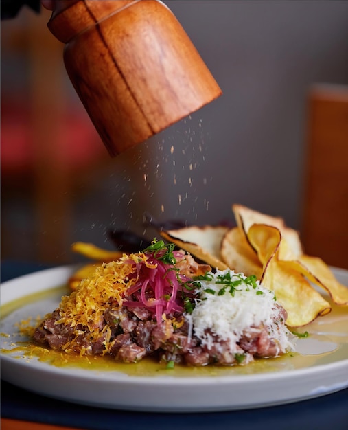 Um prato de comida com uma mão polvilhando sal sobre ele.