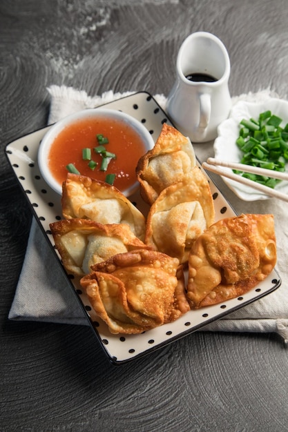 Um prato de comida com uma tigela de molho e pauzinhos