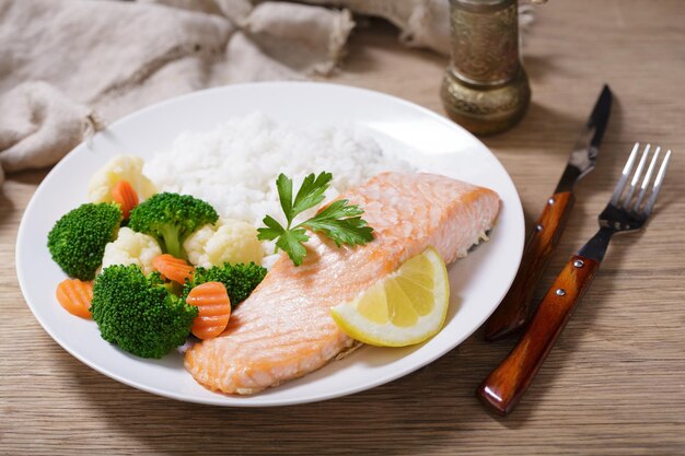 Foto um prato de filé de salmão, arroz e vegetais.
