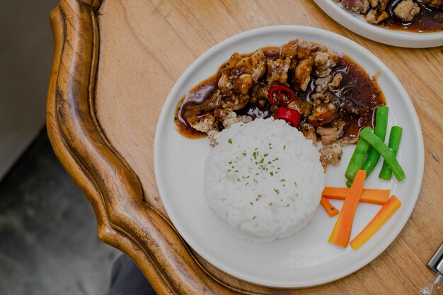 Foto um prato de frango pimenta preta com arroz e adicional de feijão verde e cenoura