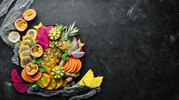 Um prato de frutas tropicais fatiadas. Vista do topo. Espaço livre para texto.