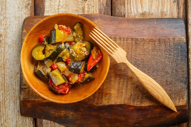 Um prato de legumes grelhados em uma tábua de madeira ao lado de um garfo de madeira