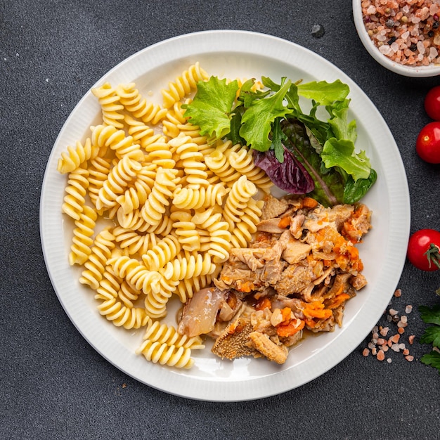 Um prato de macarrão e salada com uma salada ao lado.