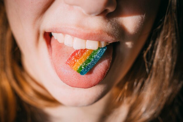 Um prato de marmelada Rainbow na língua de uma adolescente à luz do sol