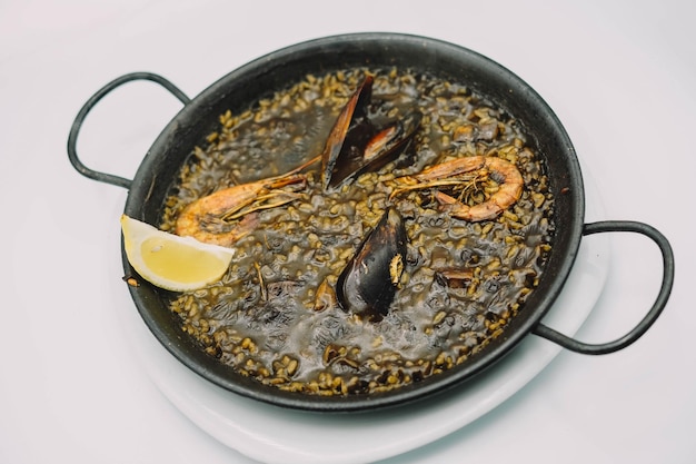 Um prato de paella de arroz preto com camarão lula e mexilhões