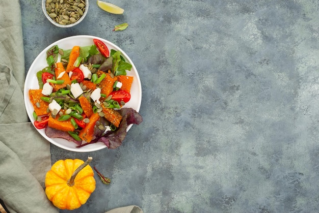 Um prato de salada com uma abóbora ao lado