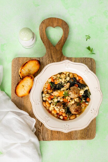 Foto um prato de sopa de minestrone caseira com almôndegas e espinafre em fundo verde