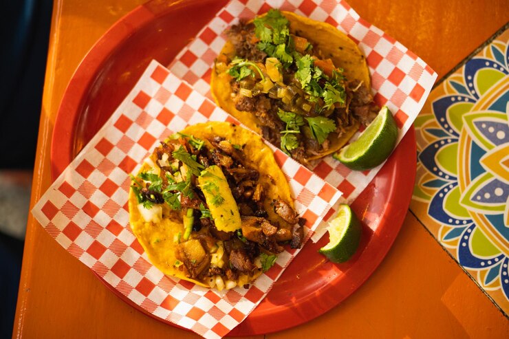 Foto um prato de tacos com um papel quadriculado vermelho com uma folha verde