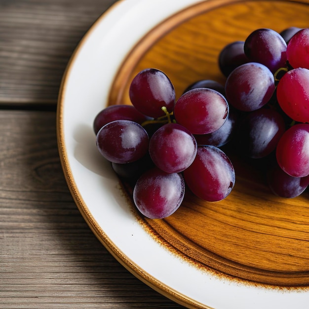 Um prato de uvas vermelhas frescas maduras em uma mesa de madeira de perto