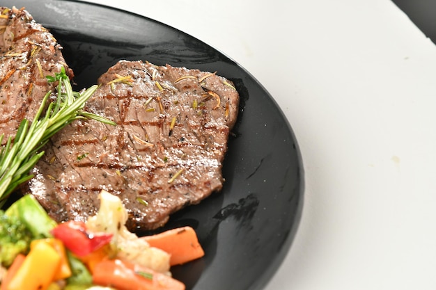 Foto um prato preto com um bife e uma salada ao lado.