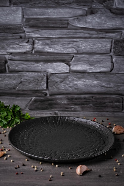 Um prato preto vazio sobre um fundo cinza com especiarias e ervas Espaço vazio para cópia Jantar em casa cozinhar