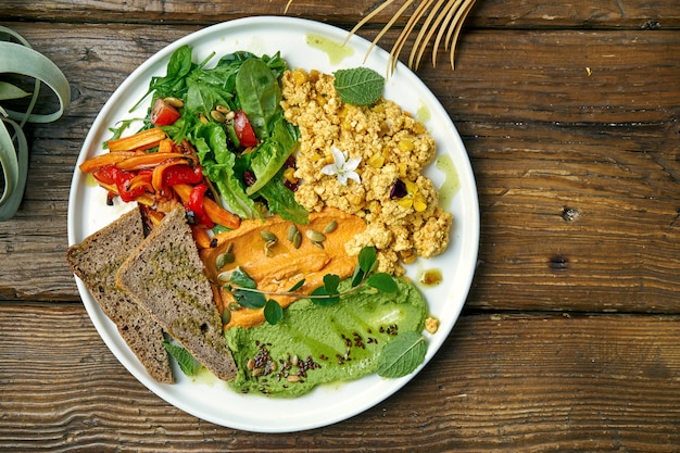 Um prato vegetariano apetitoso é a mistura de queijo tofu, salada de pimentos assados e rúcula e dois tipos de hummus. Madeira