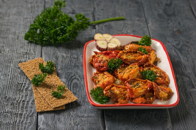 Um prato vermelho e branco de tomates secos ao sol em uma mesa de madeira. Aperitivo de tomate mediterrâneo. Comida vegetariana.