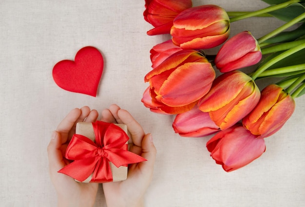 Um presente e tulipas vermelhas em um fundo claroo conceito de amor e celebração