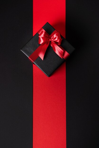 Um presente elegante em uma embalagem escura e uma fita festiva brilhante. O minimalismo é uma imagem vertical.