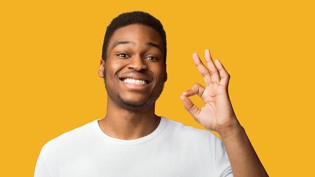 Um preto feliz a fazer um gesto de "ok" e a sorrir.