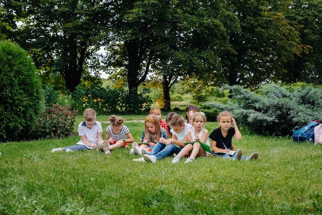 Um professor dá aula para crianças em um parque ao ar livre. de volta à escola, aprendendo durante a pandemia.