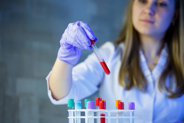 Foto um profissional médico, assistente de laboratório, médico realiza uma análise em laboratório, usa tubos de ensaio, uma pipeta e uma placa de petri para a presença de bactérias no corpo humano