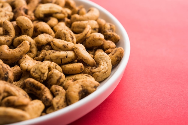 Um punhado de castanhas de caju torradas com especiarias ou masala kaju servido em uma tigela, com foco seletivo