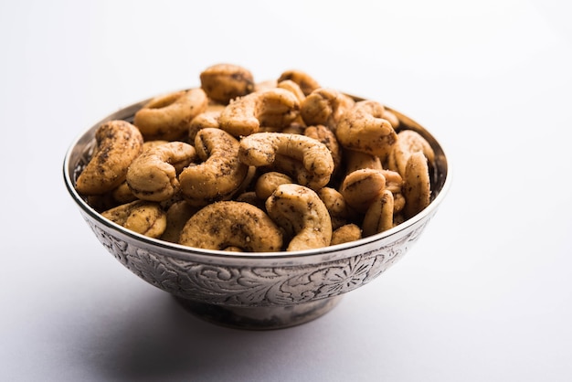 Um punhado de castanhas de caju torradas com especiarias ou masala kaju servido em uma tigela, com foco seletivo